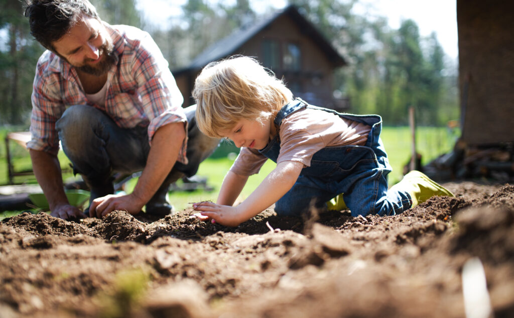 Father with small son working outdoors in garden, sustainable lifestyle concept.